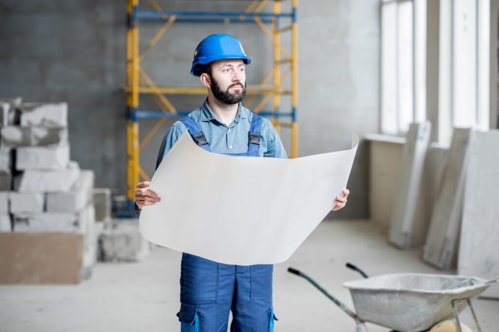 Construction worker looking at plans wondering how he's going to recruit a big enough workforce
